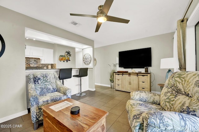 living area featuring tile patterned floors, ceiling fan, baseboards, and visible vents