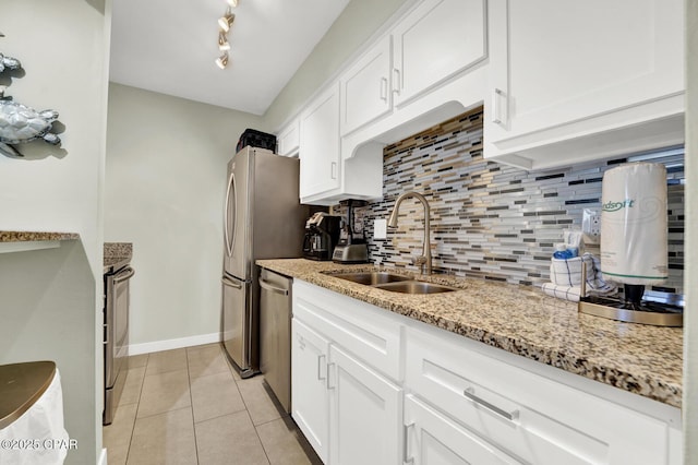 kitchen featuring decorative backsplash, white cabinets, a sink, light tile patterned floors, and stainless steel appliances