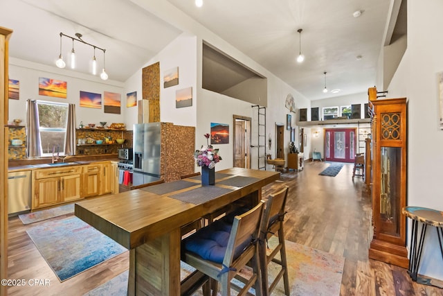 kitchen with light wood-style floors, a healthy amount of sunlight, high vaulted ceiling, and dishwasher