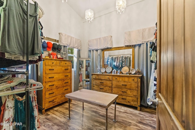 walk in closet with an inviting chandelier, wood finished floors, and high vaulted ceiling