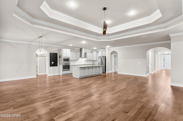 31 Viper Rd, Santa Rosa Beach, FL 32459 - unfurnished living room featuring a tray ceiling, arched walkways, wood finished floors, and crown molding