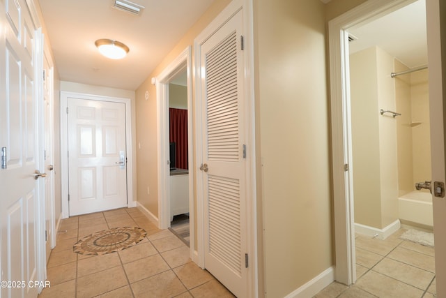 hallway featuring light tile patterned flooring, baseboards, and visible vents