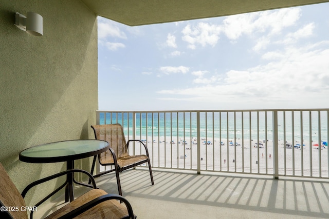 balcony with a water view and a view of the beach