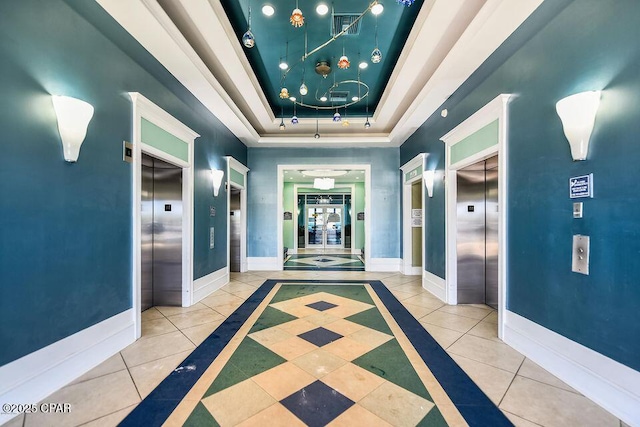 corridor featuring elevator, a tray ceiling, baseboards, and french doors