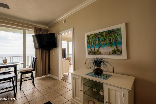 dining space featuring a textured ceiling, light tile patterned floors, baseboards, and ornamental molding