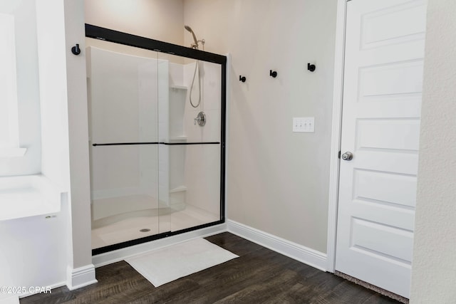 bathroom featuring baseboards, wood finished floors, and a shower stall