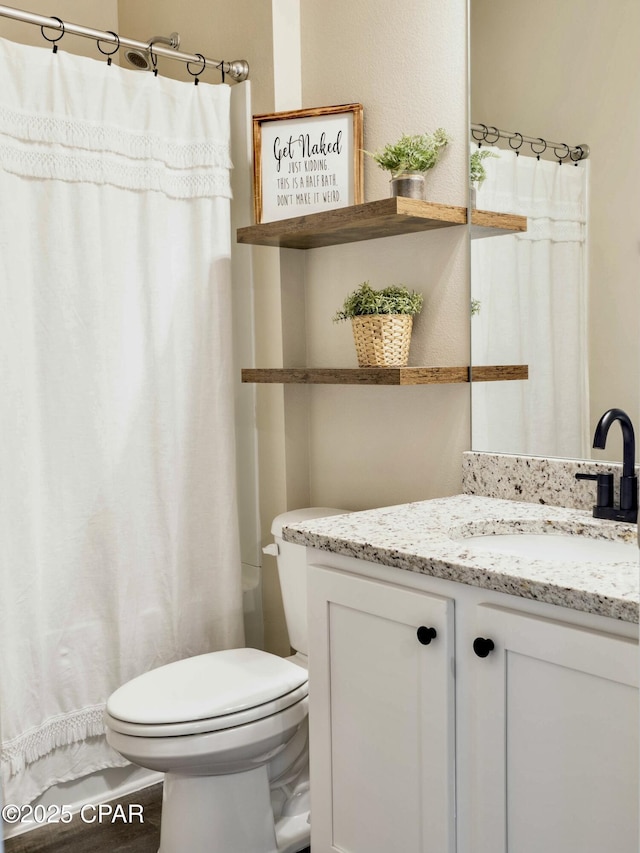 bathroom featuring curtained shower, vanity, and toilet