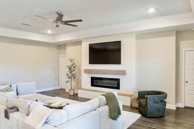 living area featuring a ceiling fan, ornamental molding, a glass covered fireplace, and dark wood-style floors