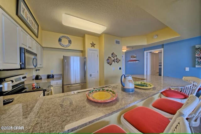 kitchen featuring white cabinets, visible vents, a textured ceiling, and appliances with stainless steel finishes