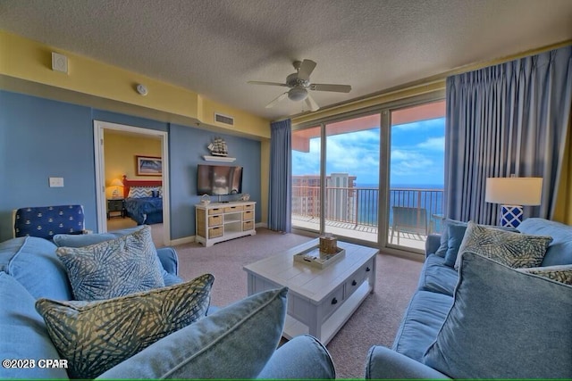 living area featuring ceiling fan, a textured ceiling, visible vents, carpet floors, and baseboards