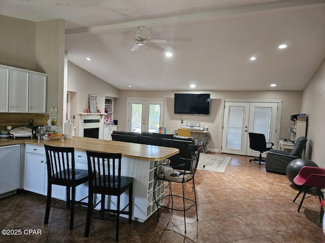 kitchen featuring a peninsula, a breakfast bar area, white cabinets, french doors, and a ceiling fan