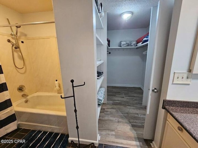full bathroom featuring vanity, a textured ceiling, wood finished floors, shower / tub combo, and a spacious closet