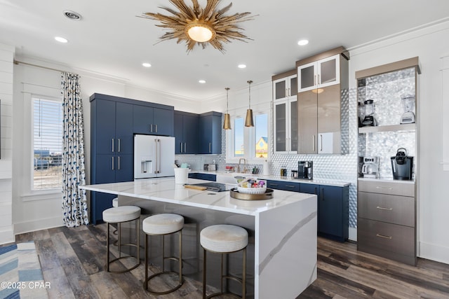 12401 Front Beach Rd, Panama City Beach, FL 32407 - kitchen featuring white refrigerator with ice dispenser, a kitchen breakfast bar, a wealth of natural light, and blue cabinetry