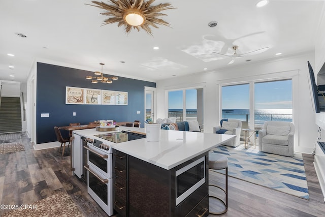 12401 Front Beach Rd, Panama City Beach, FL 32407 - kitchen with crown molding, ceiling fan with notable chandelier, dark wood-type flooring, stainless steel microwave, and range with two ovens