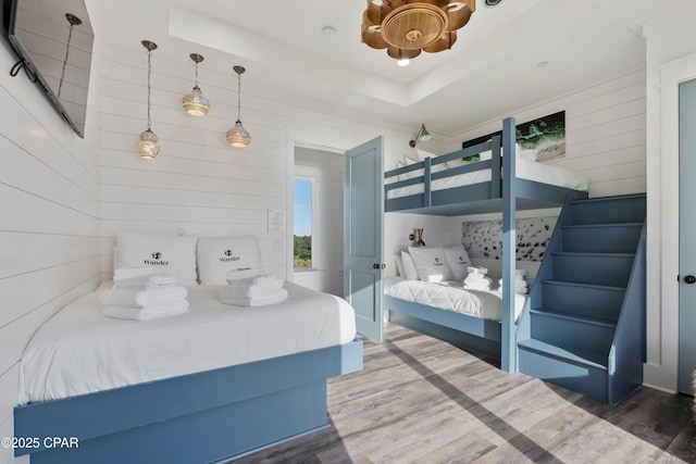 12401 Front Beach Rd, Panama City Beach, FL 32407 - bedroom featuring wooden walls, a raised ceiling, and wood finished floors