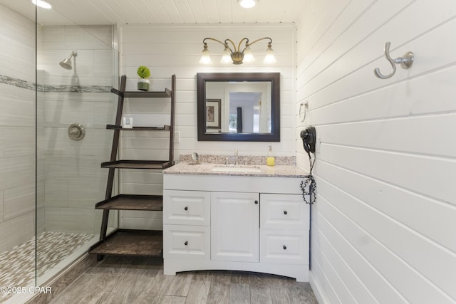 full bath with vanity, wood walls, wooden ceiling, wood finished floors, and tiled shower