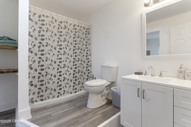 bathroom featuring vanity, a shower stall, toilet, and wood finished floors