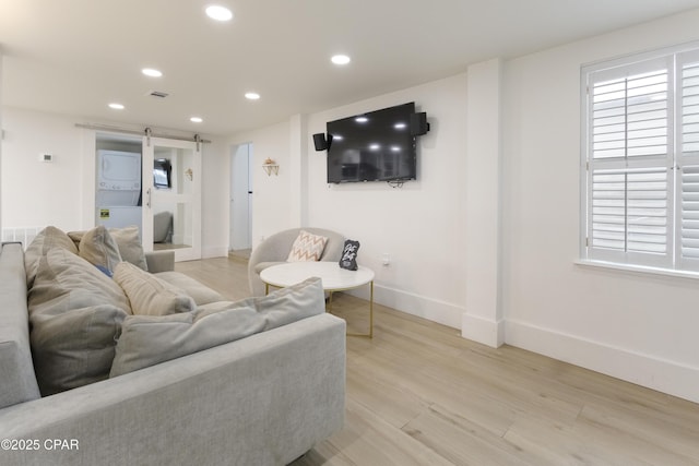 living room featuring visible vents, stacked washer and clothes dryer, baseboards, recessed lighting, and light wood-style flooring