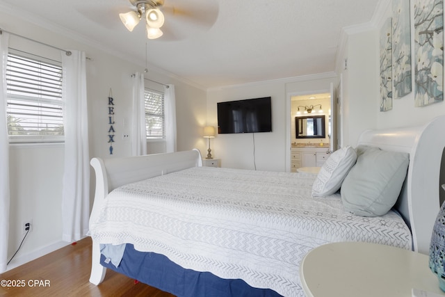 bedroom featuring ornamental molding, wood finished floors, baseboards, ensuite bathroom, and a ceiling fan