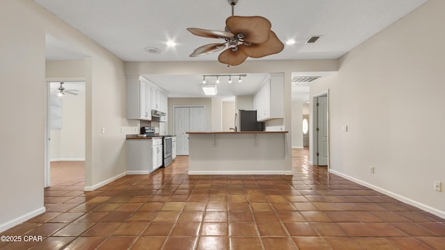 kitchen featuring stainless steel electric range oven, freestanding refrigerator, white cabinetry, and a ceiling fan