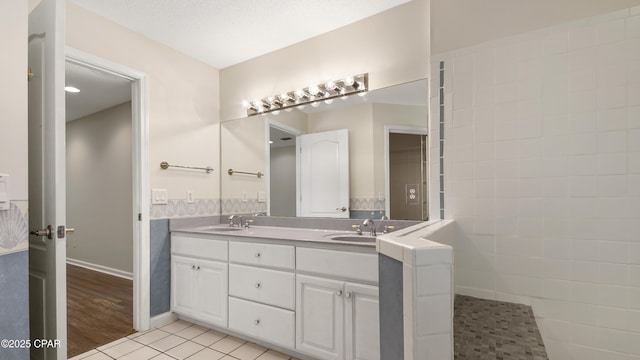 full bath featuring tile patterned floors, double vanity, a sink, and baseboards