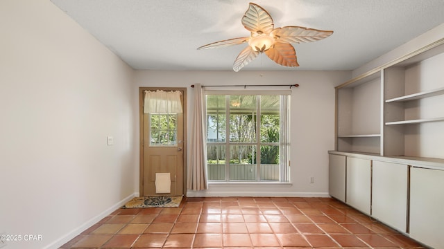 entryway with baseboards, a ceiling fan, light tile patterned flooring, and a textured ceiling