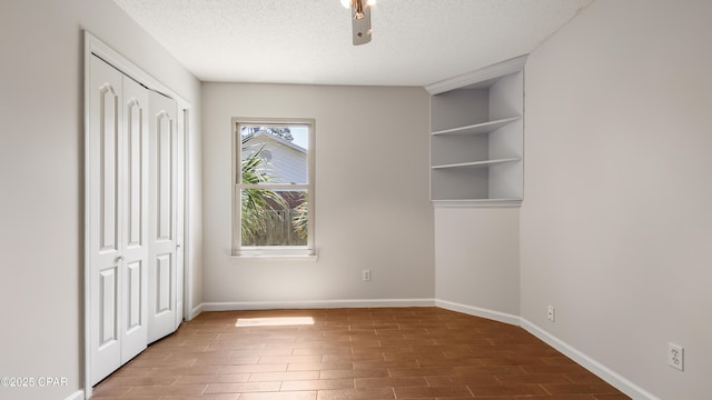 unfurnished bedroom featuring a closet, baseboards, wood finished floors, and a textured ceiling