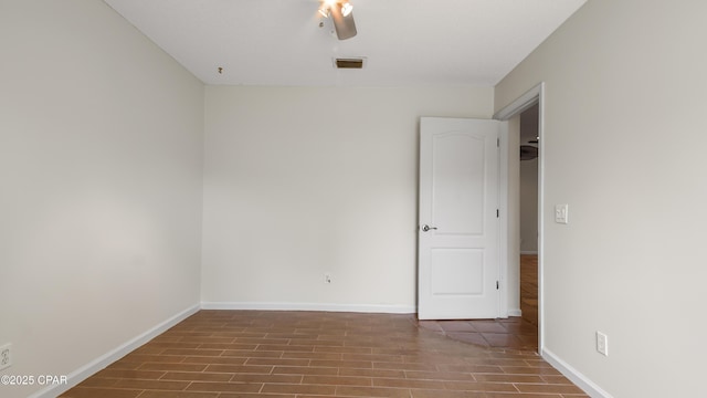 empty room with wood finished floors, ceiling fan, baseboards, and visible vents