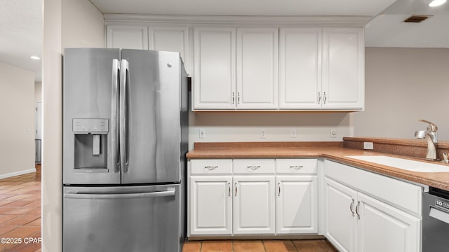 kitchen with white cabinets, visible vents, dishwasher, a sink, and stainless steel fridge