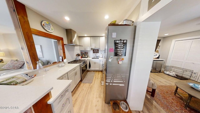 1314 Mcclelland Ave, Port St Joe, FL 32456 - kitchen featuring appliances with stainless steel finishes, wall chimney exhaust hood, light wood-style flooring, white cabinets, and recessed lighting