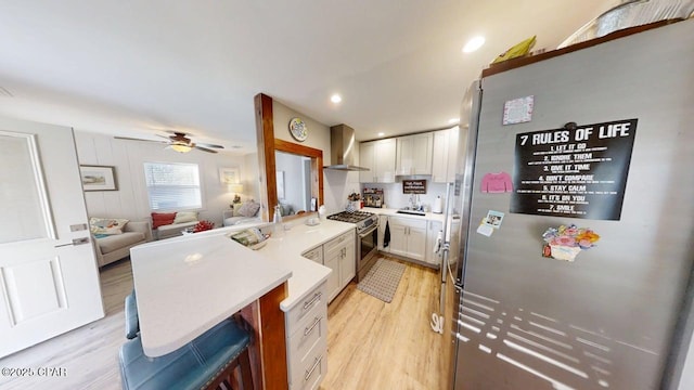 1314 Mcclelland Ave, Port St Joe, FL 32456 - kitchen with appliances with stainless steel finishes, a peninsula, wall chimney range hood, light wood-style floors, and recessed lighting