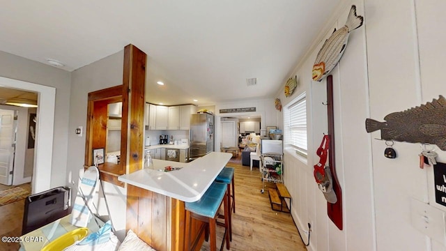 1314 Mcclelland Ave, Port St Joe, FL 32456 - kitchen with freestanding refrigerator, light countertops, a kitchen breakfast bar, light wood-type flooring, and a peninsula