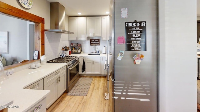1314 Mcclelland Ave, Port St Joe, FL 32456 - kitchen featuring wall chimney range hood, stainless steel appliances, light wood finished floors, decorative backsplash, and white cabinets