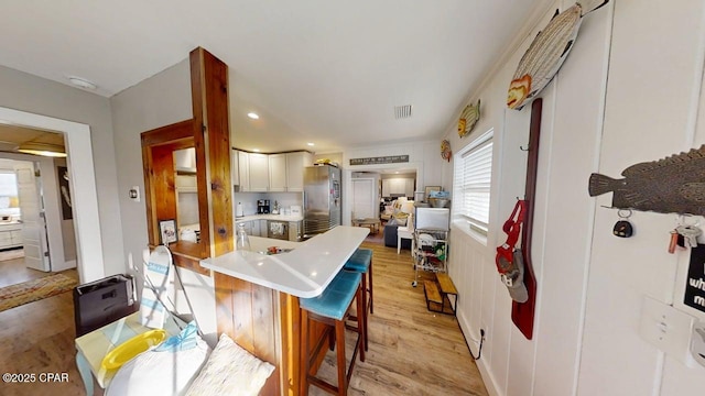 1314 Mcclelland Ave, Port St Joe, FL 32456 - kitchen with freestanding refrigerator, light wood finished floors, a kitchen bar, light countertops, and white cabinets