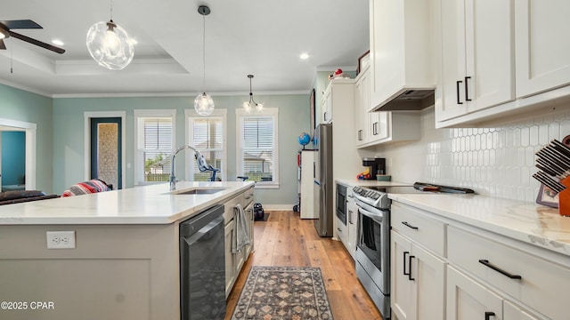 kitchen with crown molding, a tray ceiling, tasteful backsplash, appliances with stainless steel finishes, and a sink