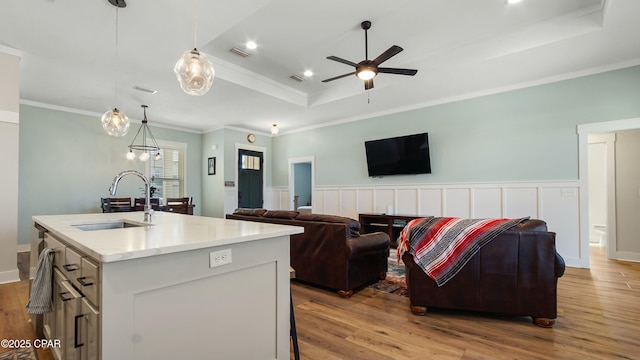 kitchen featuring a raised ceiling, open floor plan, visible vents, ceiling fan, and a sink