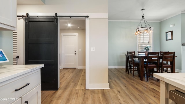 kitchen with light wood-type flooring, baseboards, white cabinets, a chandelier, and ornamental molding