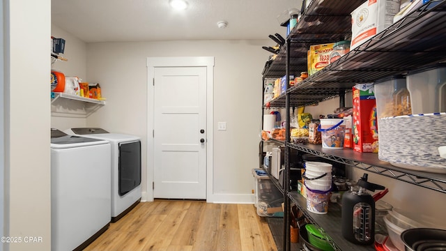 laundry room with light wood-type flooring, separate washer and dryer, and laundry area