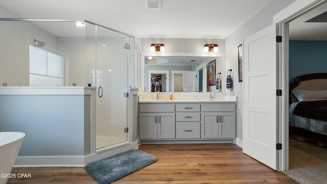bathroom with connected bathroom, a stall shower, wood finished floors, double vanity, and a soaking tub