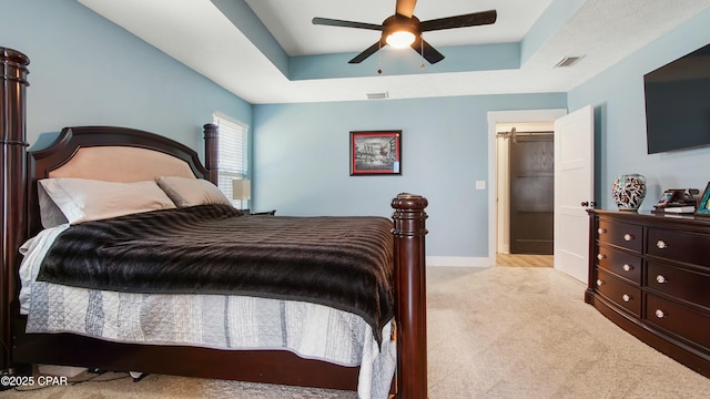 carpeted bedroom with a tray ceiling, ceiling fan, baseboards, and visible vents