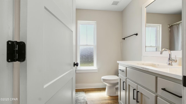 bathroom with visible vents, baseboards, toilet, vanity, and wood finished floors