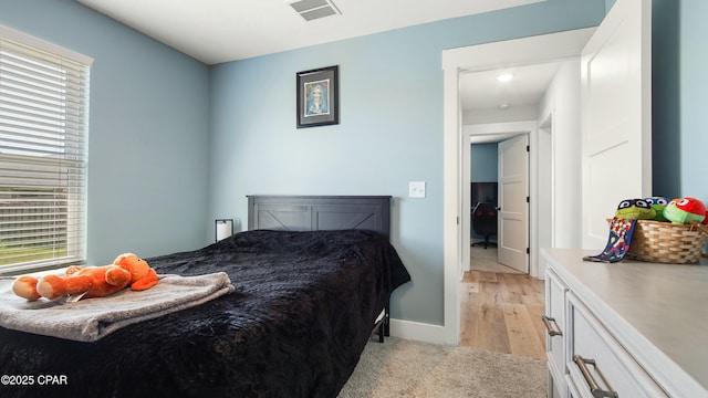 bedroom with multiple windows, baseboards, and light wood finished floors