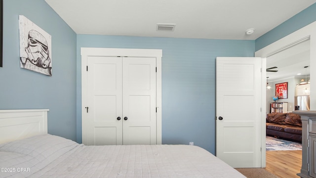 bedroom with a closet, wood finished floors, and visible vents