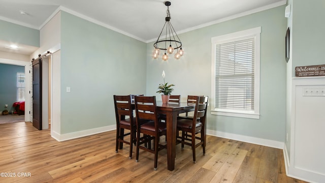 dining room with baseboards, an inviting chandelier, a barn door, ornamental molding, and light wood-type flooring