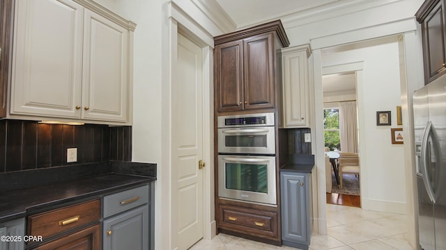 kitchen featuring crown molding, dark countertops, stainless steel appliances, and baseboards