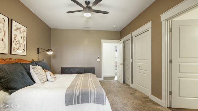 bedroom with carpet floors, a ceiling fan, visible vents, baseboards, and multiple closets
