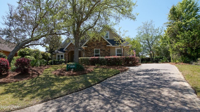 craftsman house featuring driveway, a front lawn, and stone siding