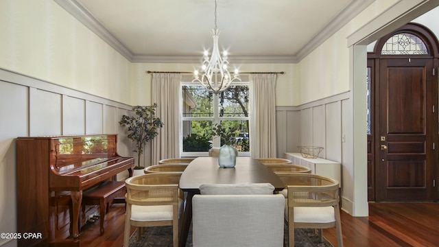 dining area with ornamental molding, dark wood-style floors, a chandelier, and a decorative wall