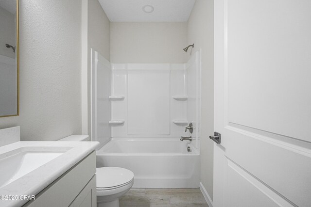 bathroom featuring toilet, wood finished floors, vanity, and  shower combination