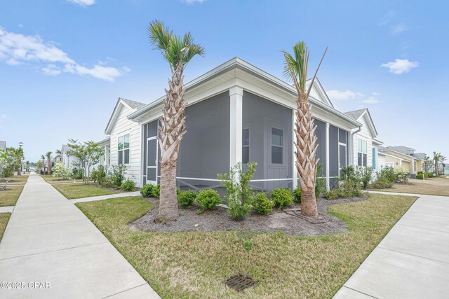 view of side of home featuring a yard, a residential view, and a sunroom